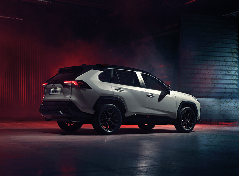 Biała Toyota RAV4 z zapalonymi światłami